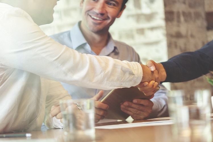 Three businessmen meeting in a board room closing a deal.